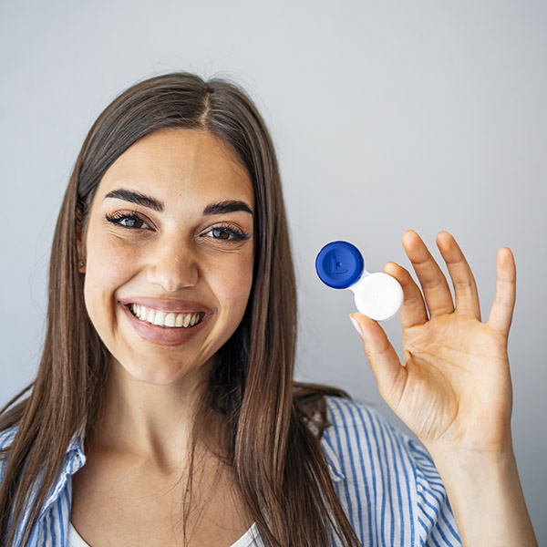 Woman holding plastic container with contact lenses, indoors